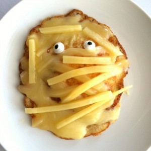 cheesy egg mummy with googly eyes on a white plate on shockinglydelicious.com