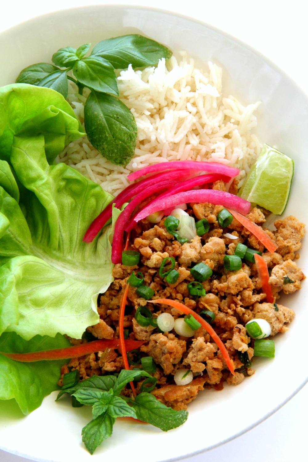 thai turkey rice bowl in a white bowl on a white counter with bright vegetables on top