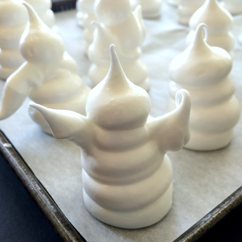 Halloween Ghost Meringue Cookies are piped out and lined up on a baking sheet