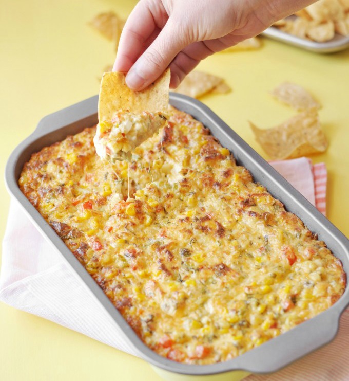 spicy-corn-dip-by-rachel-hollis in a gray baking dish against a yellow background