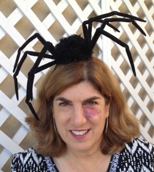 spider fascinator hat on dorothy reinhold of shockinglydelicious-com. She stands against a white lattice fence.