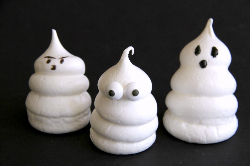 3 halloween ghost meringue cookies with a variety of eyes against a black backgroundkinglydelicious-com