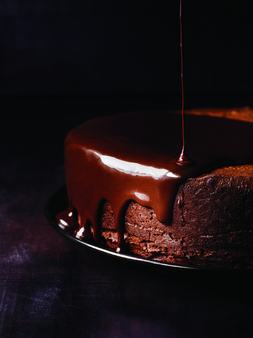 darkest-chocolate-cake-with-red-wine-glaze against a dark background