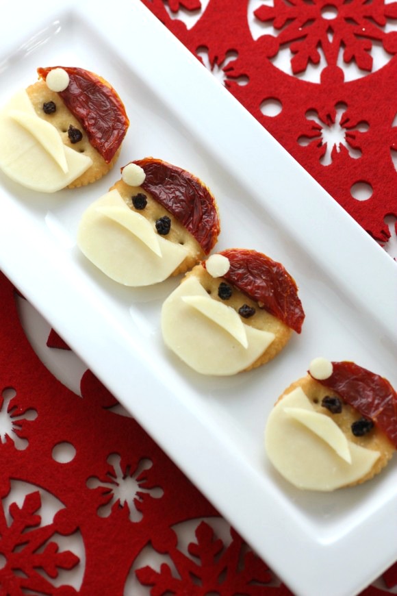 4 Santa crackers on a white plate against a red background