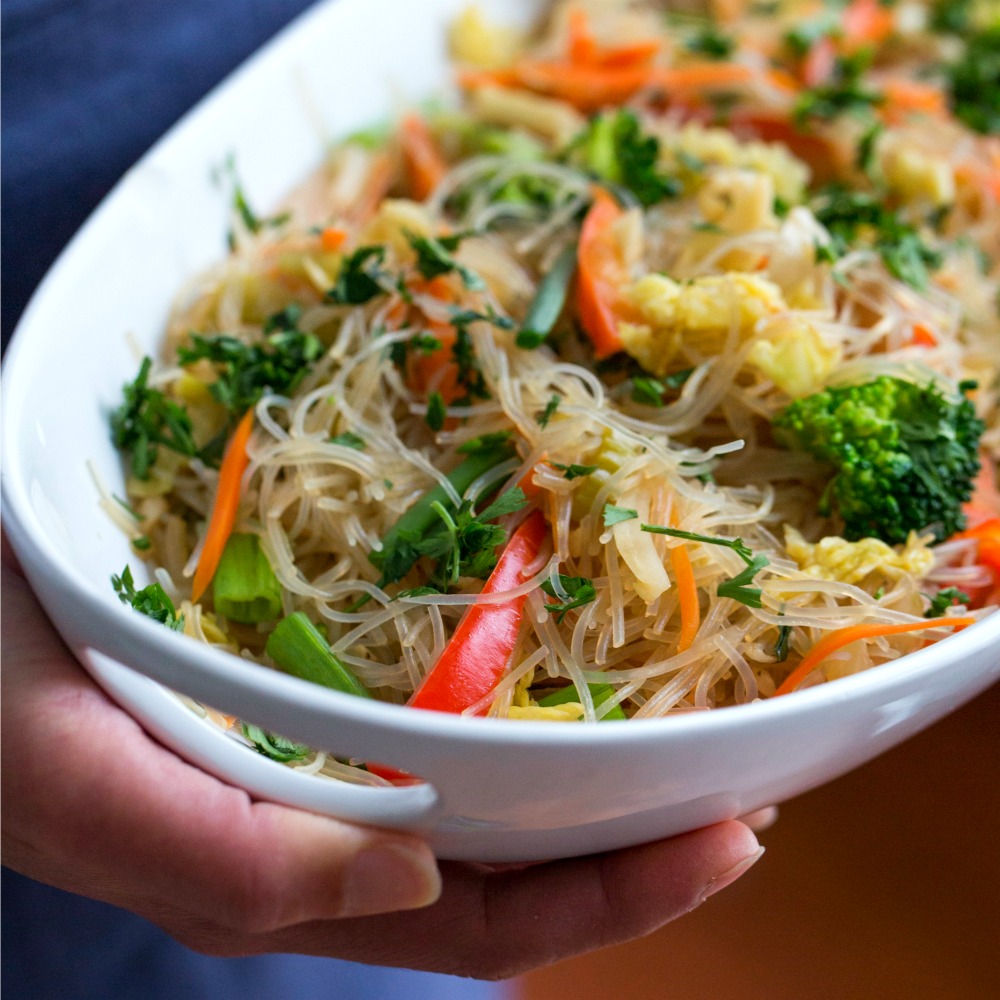 Stir-Fried Cellophane Noodles in a white bowl held with hands showing