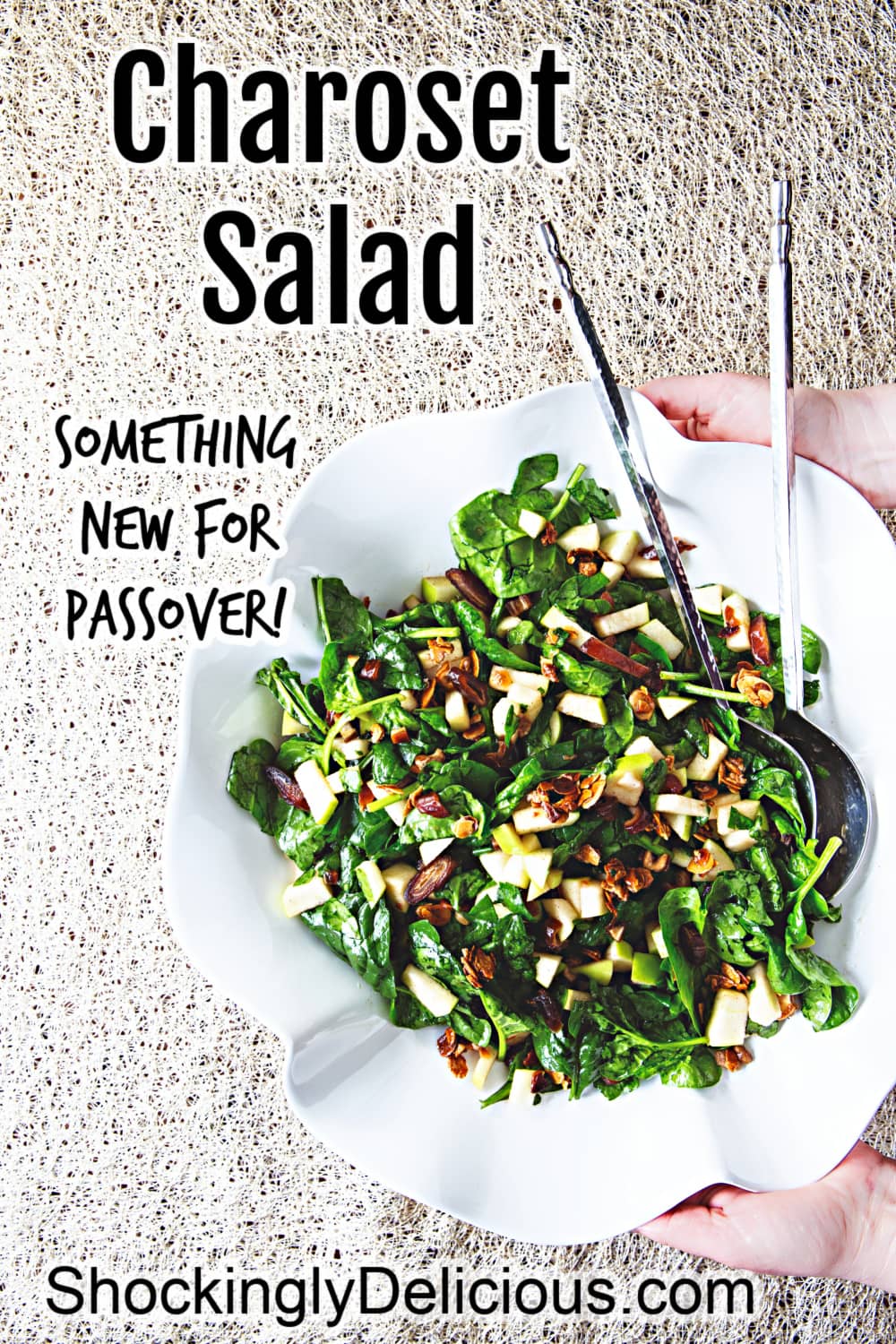 Leafy green salad with apples and nuts in a white bowl being held above a beige textured background