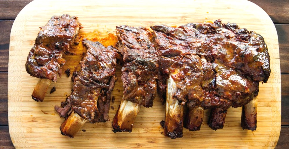 Rack of 7 meaty ribs with bones on a wooden cutting board 