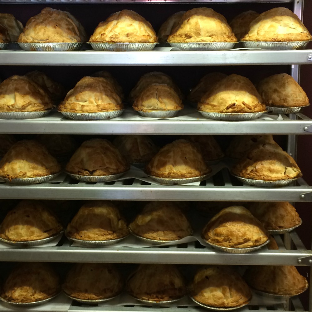 Mile-High Apple Pie from Apple Annie's in Oak Glen Calif lined up on shelves of a cooling rack