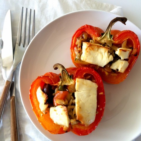 2 Enjoya striped peppers stuffed with Mediterranean orzo salad topped with feta on a white plate