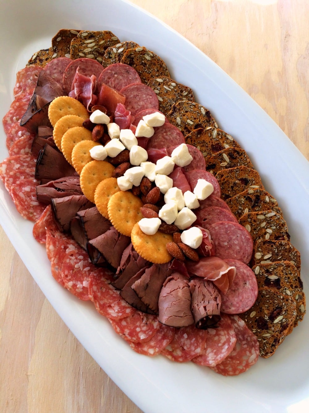 Meat and cheese arranged in the shape of a football on a white oval platter