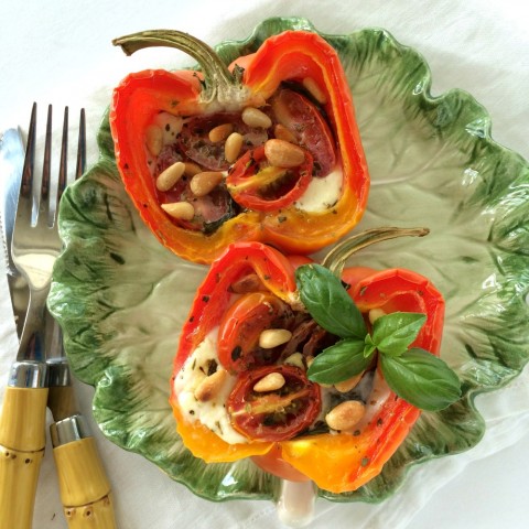 Striped bell peppers stuffed with Caprese ingredients on a green ceramic lettuce plate against a white background Peppers on ShockinglyDelicious.com