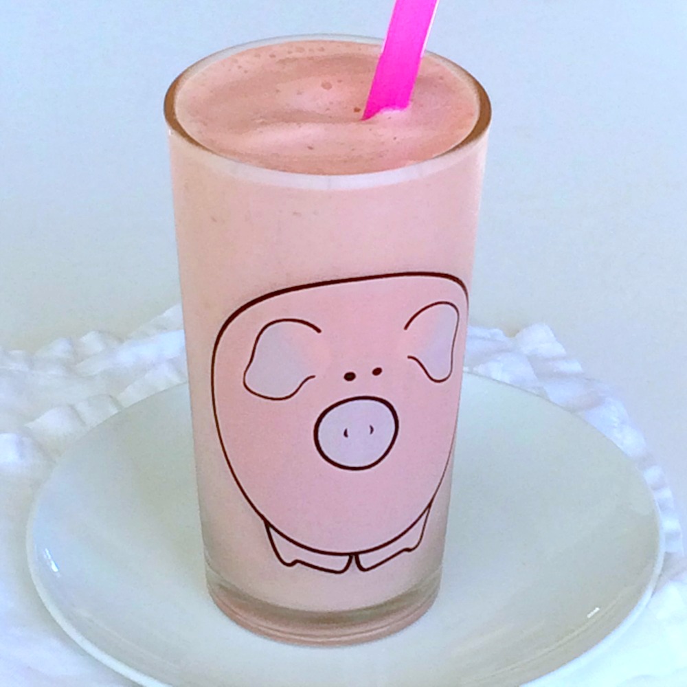 Pineapple Blood Orange Smoothie recipe in a glass decorated with a pink pig