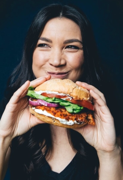 Author photo_Lauren Toyota holding a sandwich and eating it. 