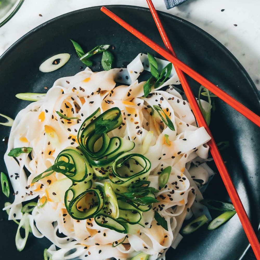 Cold Cucumber Chile Noodles in a black bowl with red chopsticks resting on the bowl