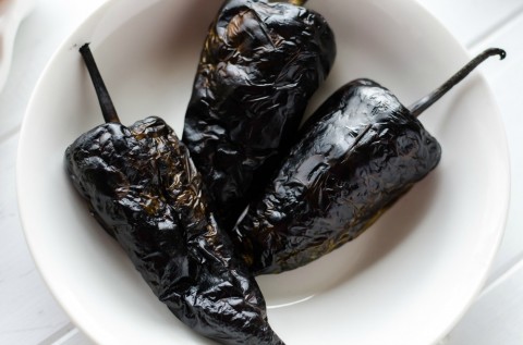 Blackened poblano chiles in a white bowl for Overnight Mexican Breakfast Casserole