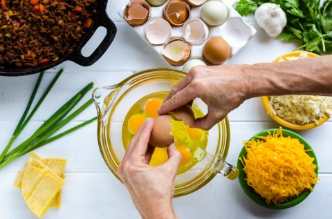 Cracking eggs in a glass bowl for Overnight Mexican Breakfast Casserole