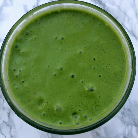 Teenage Boy Protein Smoothie -- green spinach banana smoothie in a glass on a marble background