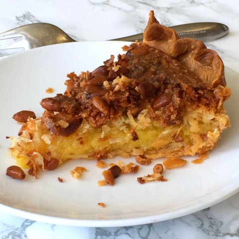 French Coconut Pie with Pine Nuts ready to be eaten on a white plate and marble background