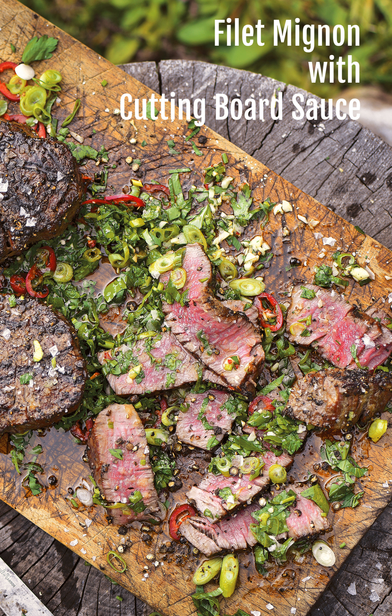 Filet Mignon rests on a wooden cutting board with herbs on ShockinglyDelicious.com