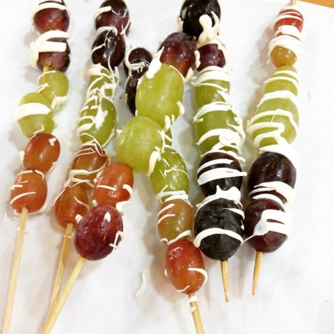 Grapes on a stick on a white plate with white chocolate drizzle