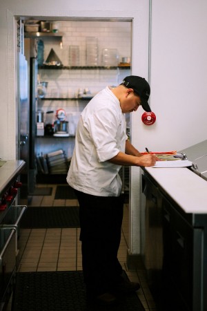 Chef Victor Rosales working on a clipboard in the kitchen at The Sparrow Club Malibu