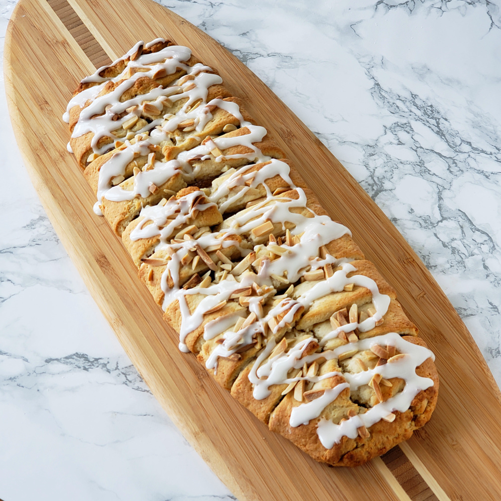 Oblong pastry on a wooden surfboard cutting board