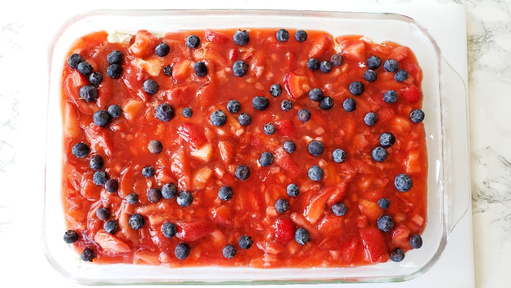 Strawberry blueberry layer on top in a glass dish on a white board