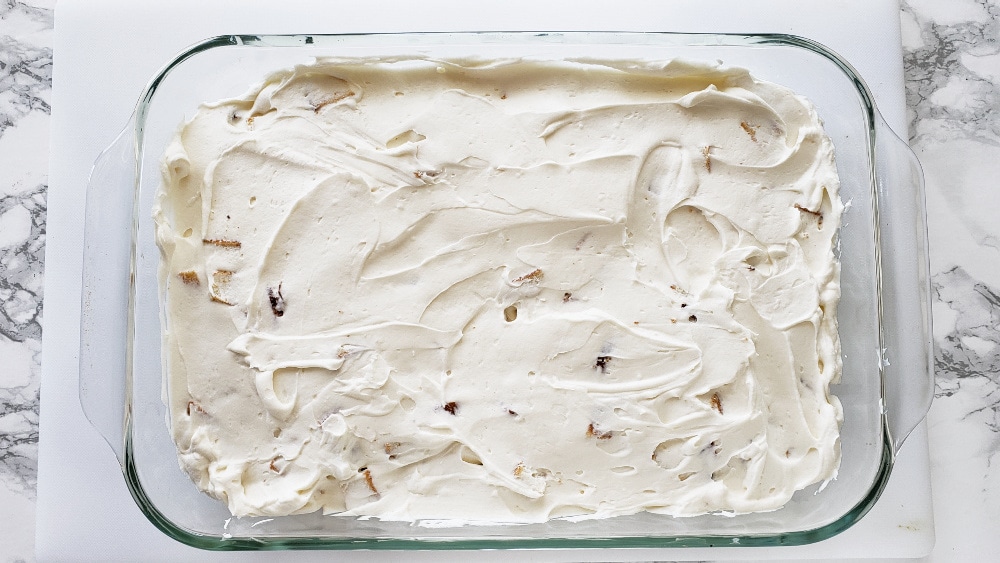 Whipped cream layer completely covers the cake layer in a glass dish on a white boardes on ShockinglyDelicious.com