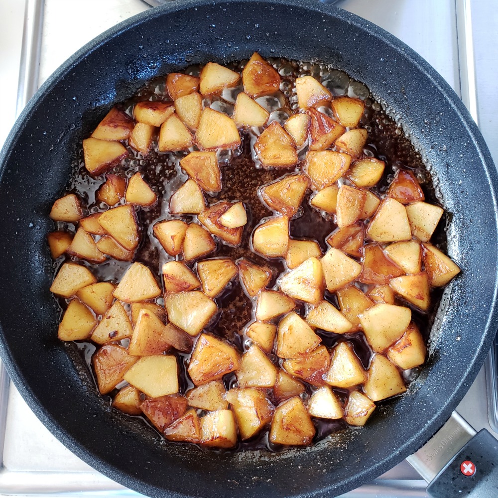 Browned apples, maple syrup and cinnamon sauce in black skillet