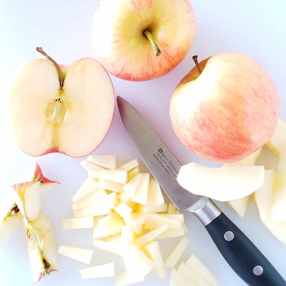 3 apples on a white cutting board being sliced on ShockinglyDelicious.com