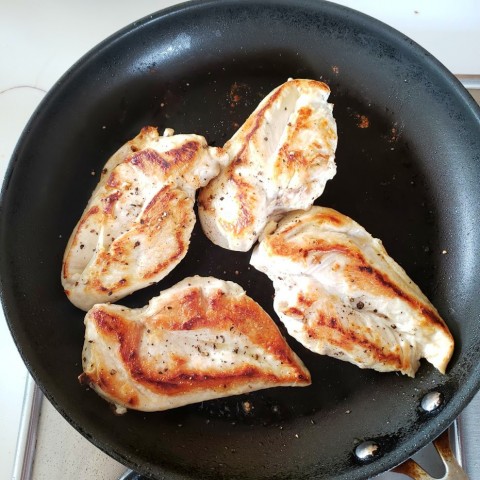 Chicken breasts cooking in a skillet on ShockinglyDelicious.com
