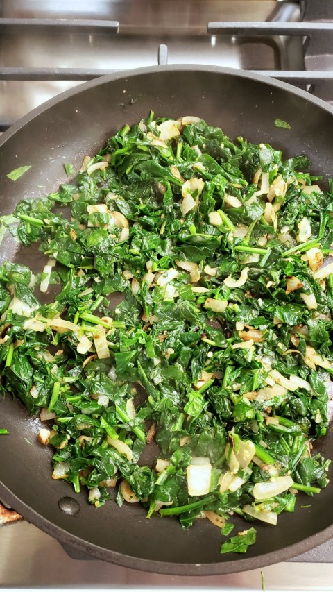 Onions and spinach in the skillet for Turkey Spanakopita Burgers on ShockinglyDelicious.com