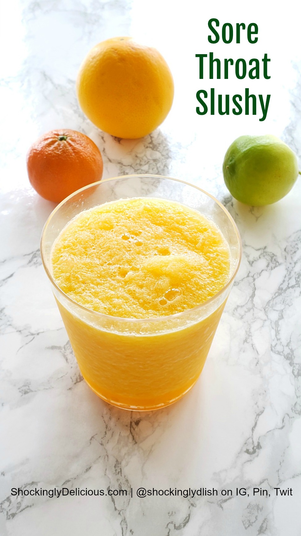 Sore Throat Slushy with a tangerine, orange and lime behind it on a white marble countertop
