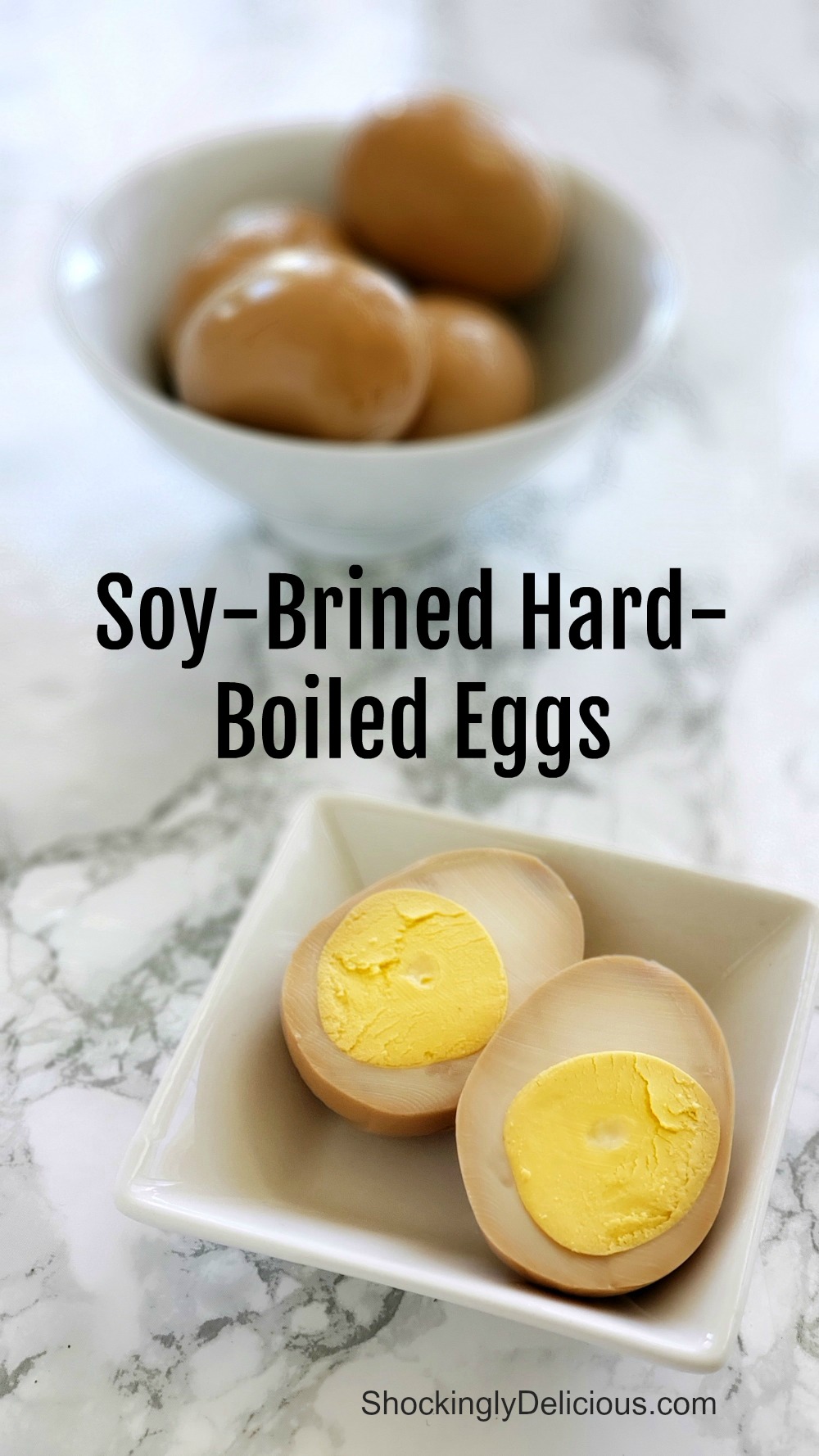 1 Soy-Brined Hard-Boiled Egg cut apart with insides showing in the foreground, and a white bowl with 4 whole soy-brined eggs in the background, on a white marple counter