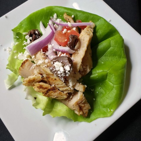 Taco mediterráneo en hoja de lechuga en plato blanco de The Black Trumpet