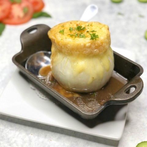 Sopa de cebolla servida en una cebolla real, en una fuente de horno marrón, en ShockinglyDelicious.com