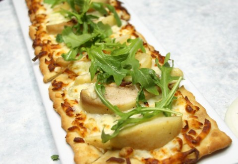 Pizette pera with roasted pear, baby arugula, Gorgonzola and mozzarella on a long rectangular white plate on ShockinglyDelicious.com