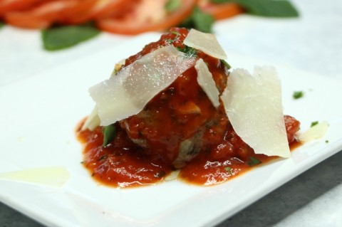 Albóndiga de ternera con marinara de la casa y pecorino raspado en un plato blanco en ShockinglyDelicious.com