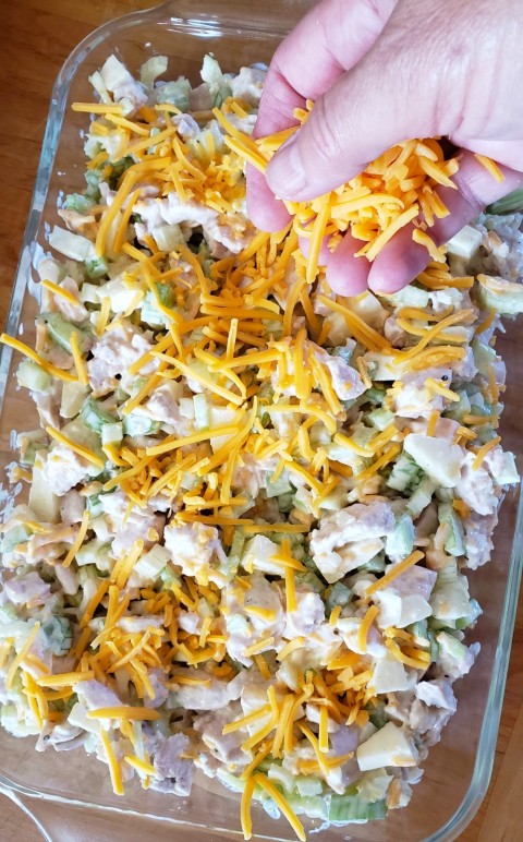 Sprinkle Cheddar Cheese on the Hot Chicken Salad on ShockinglyDelicious.com