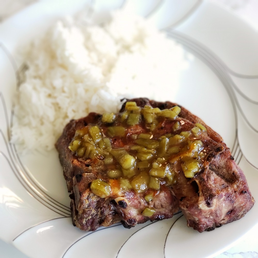 2-Ingredient Hatch Chile Marmalade on top of a lamb chop, with rice on the white plate