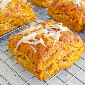 Square orange colored Pumpkin Cheddar Biscuits on a wire cooling rack