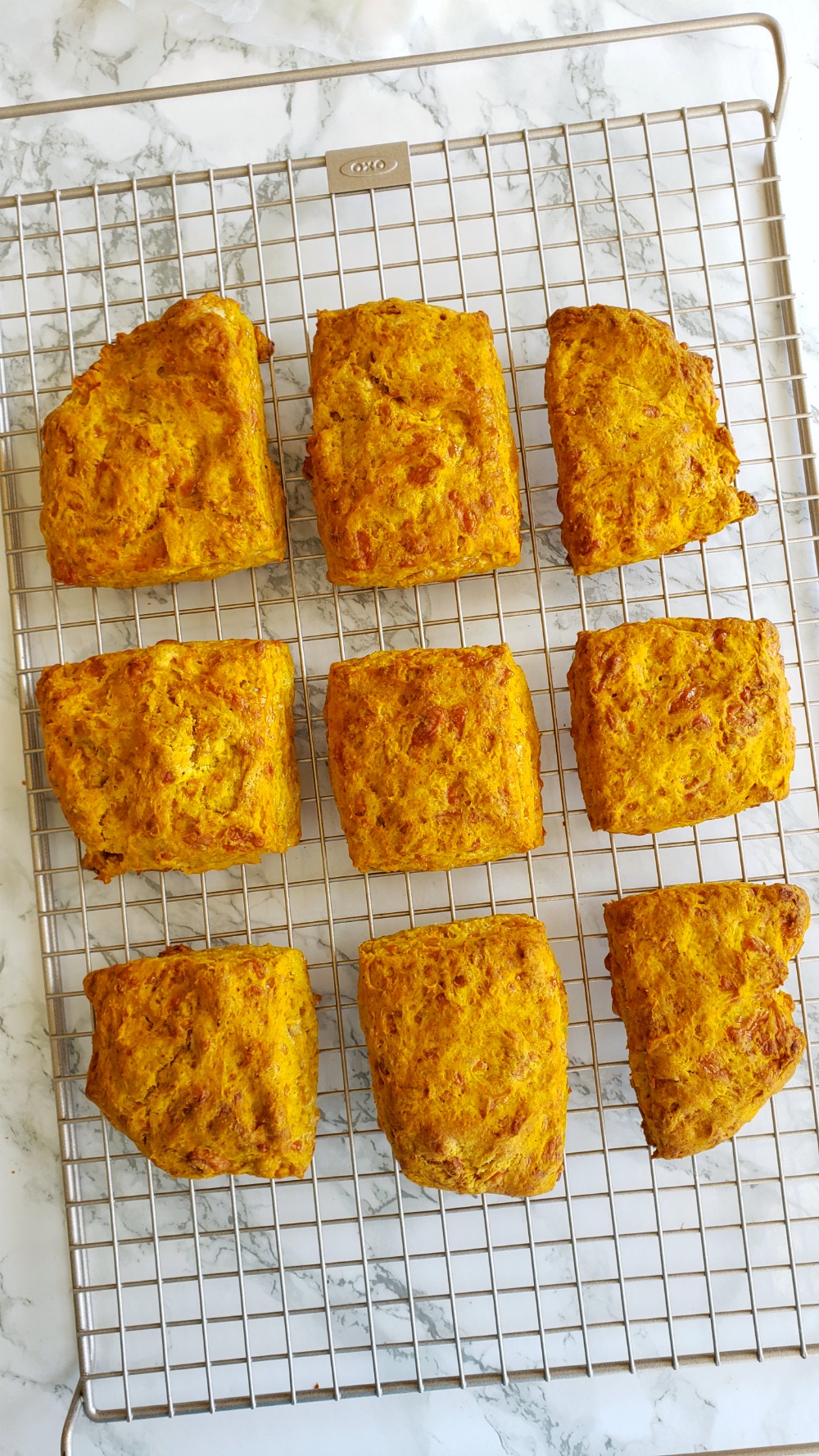 Pumpkin Cheddar Biscuits baked and out of oven on a wire cooling rack on ShockinglyDelicious.com