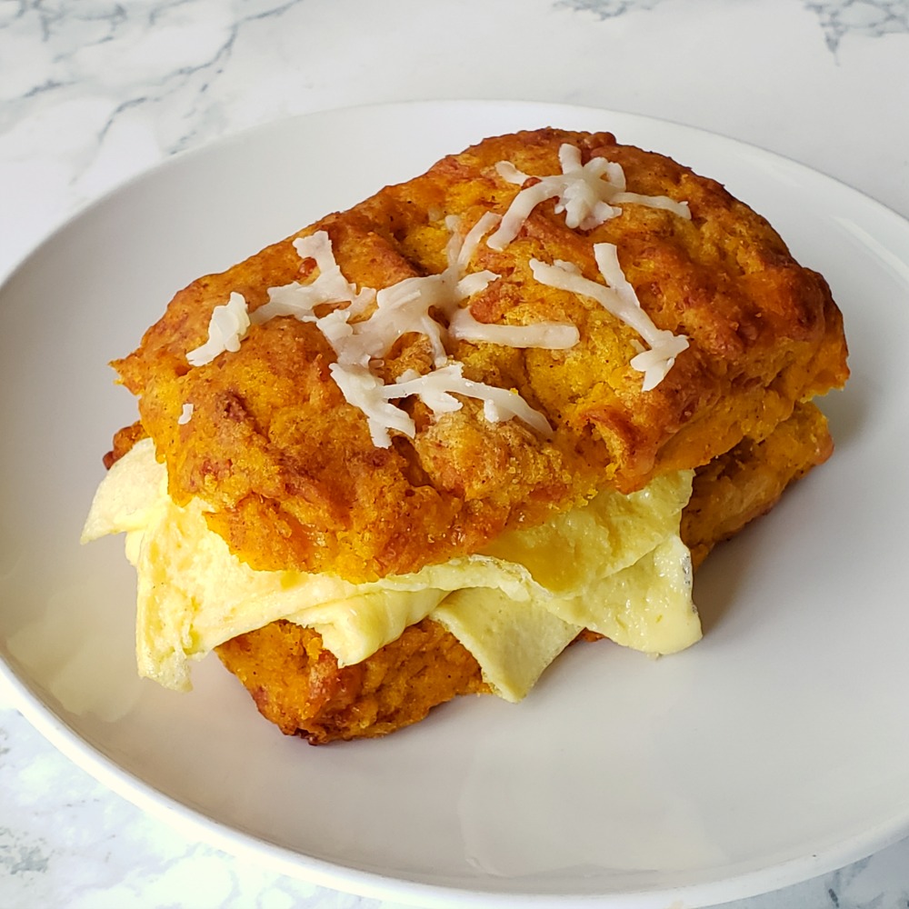 Pumpkin Cheddar Biscuits with scrambled egg inside on a white plate for breakfast on ShockinglyDelicious.com