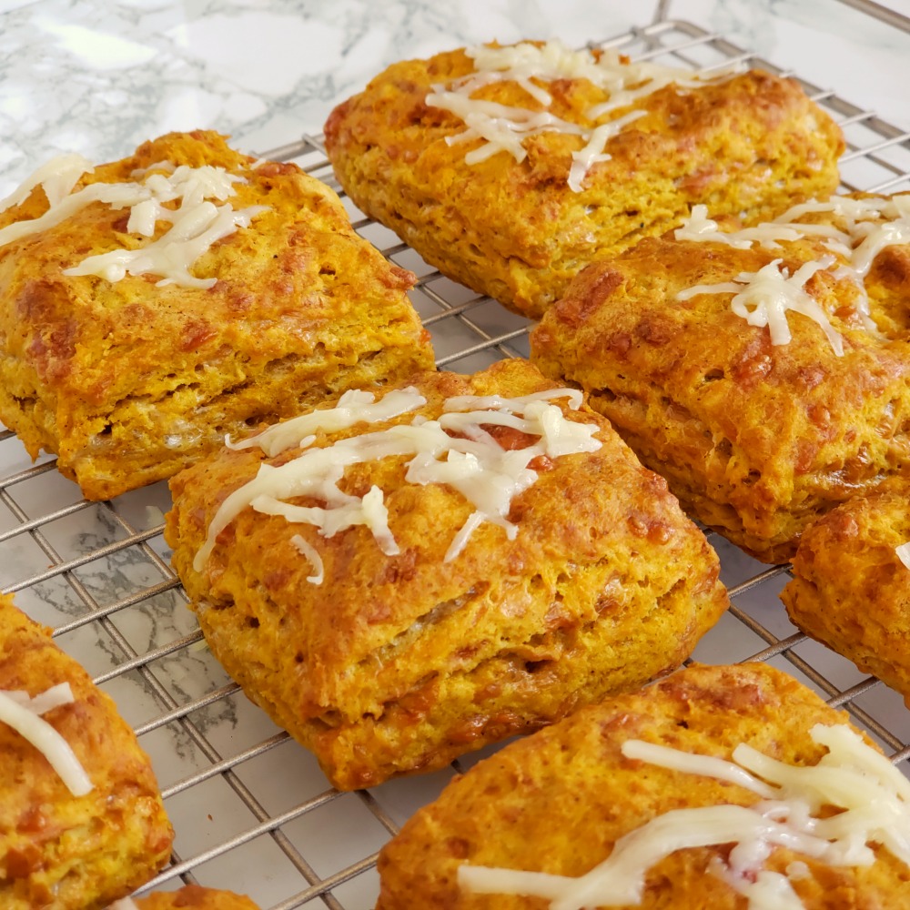 Savory Pumpkin Cheddar Biscuits on grey wire cooling rack on a white marble counter on ShockinglyDelicious.com