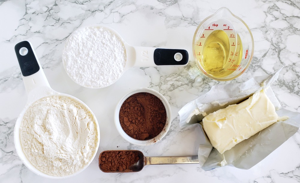 Ingredients for Rich Chocolate Shortbread Cookies on a white marble counter on ShockinglyDelicious.com