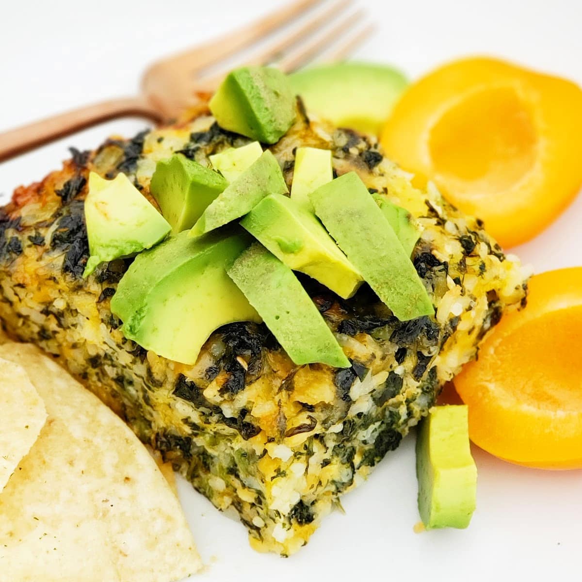 Spinach Rice Casserole topped with chopped avocado with corn chips and apricot on the side