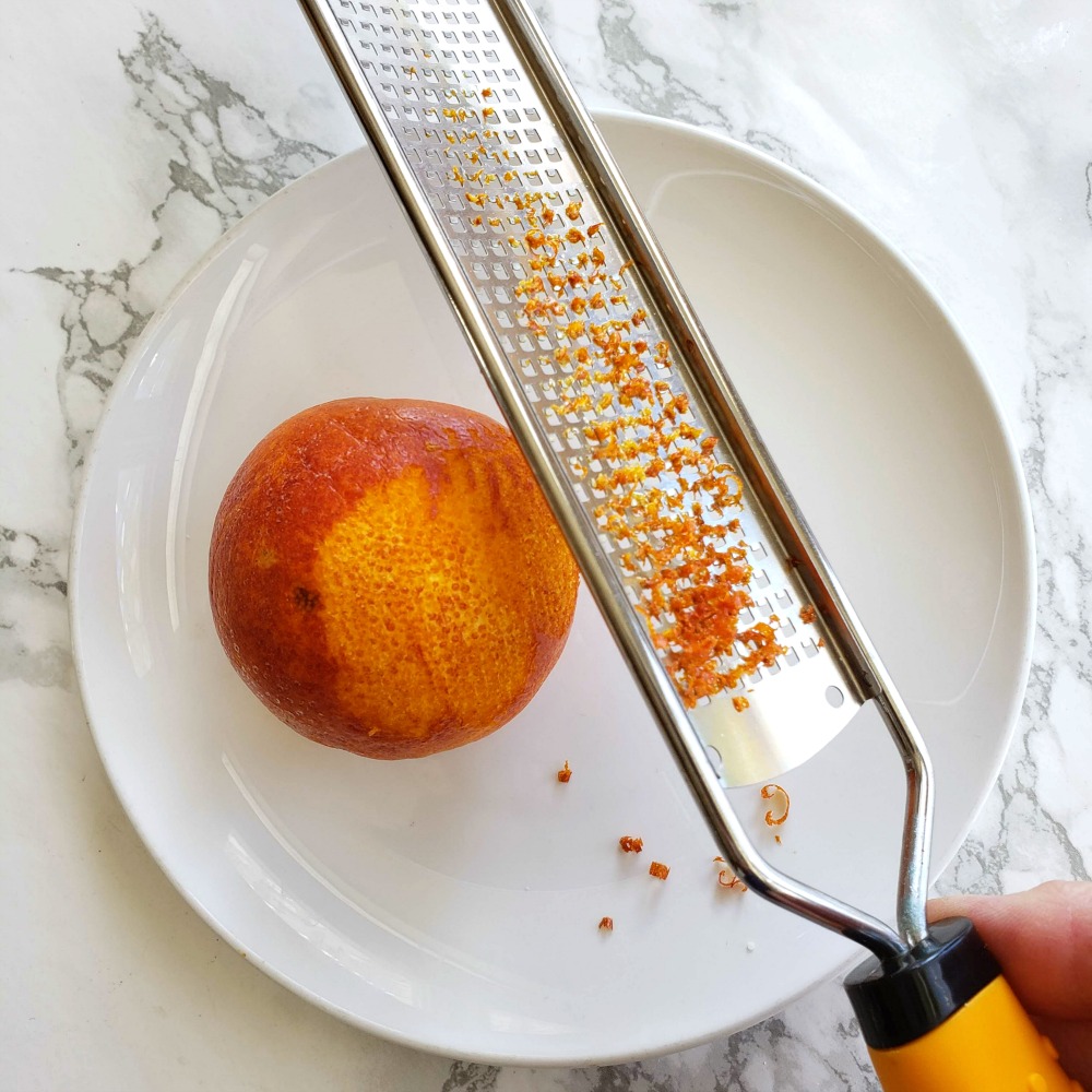 Zesting an orange on a white plate