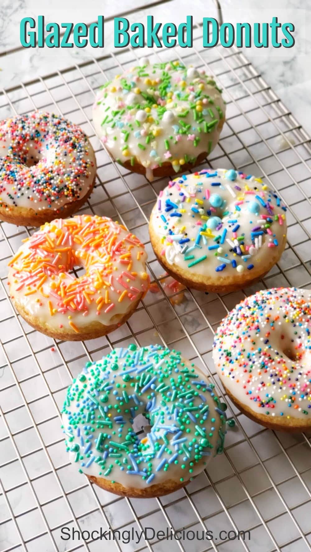 6 Glazed Baked Donuts with sprinkles on a cooling rack on a white counter