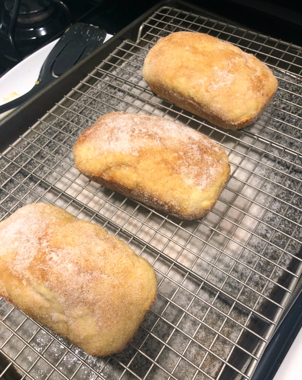 3 mini loaves of Cinnamon Doughnut Muffins made into bread loaves, on a cooling rack. 