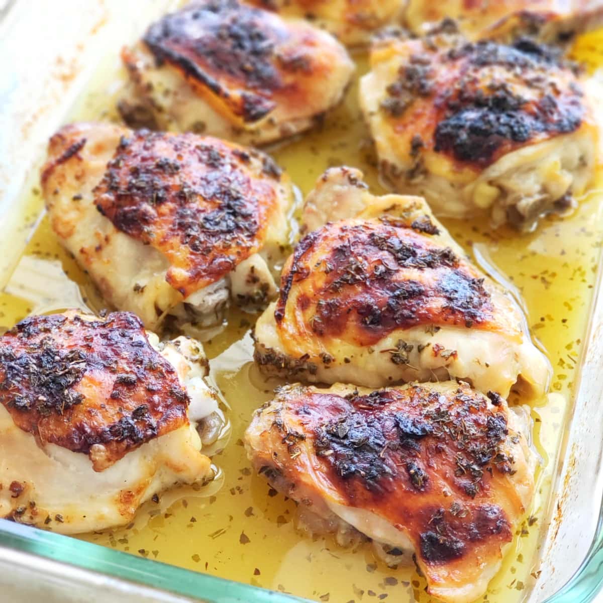 6 roasted chicken thighs in yellow sauce in a glass baking dish